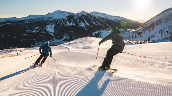 TH_ThomasSobian_Piste_zweiSkifahrer_See_Sonne